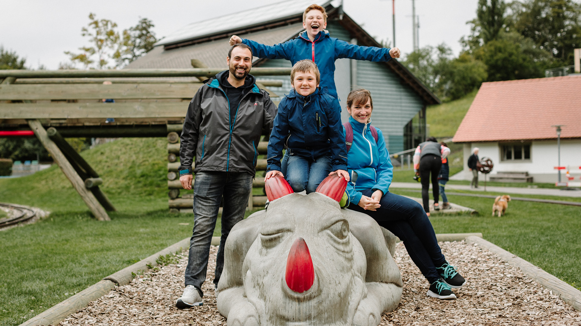 Eine Familie posiert beim Spielplatz auf dem Betondrachen