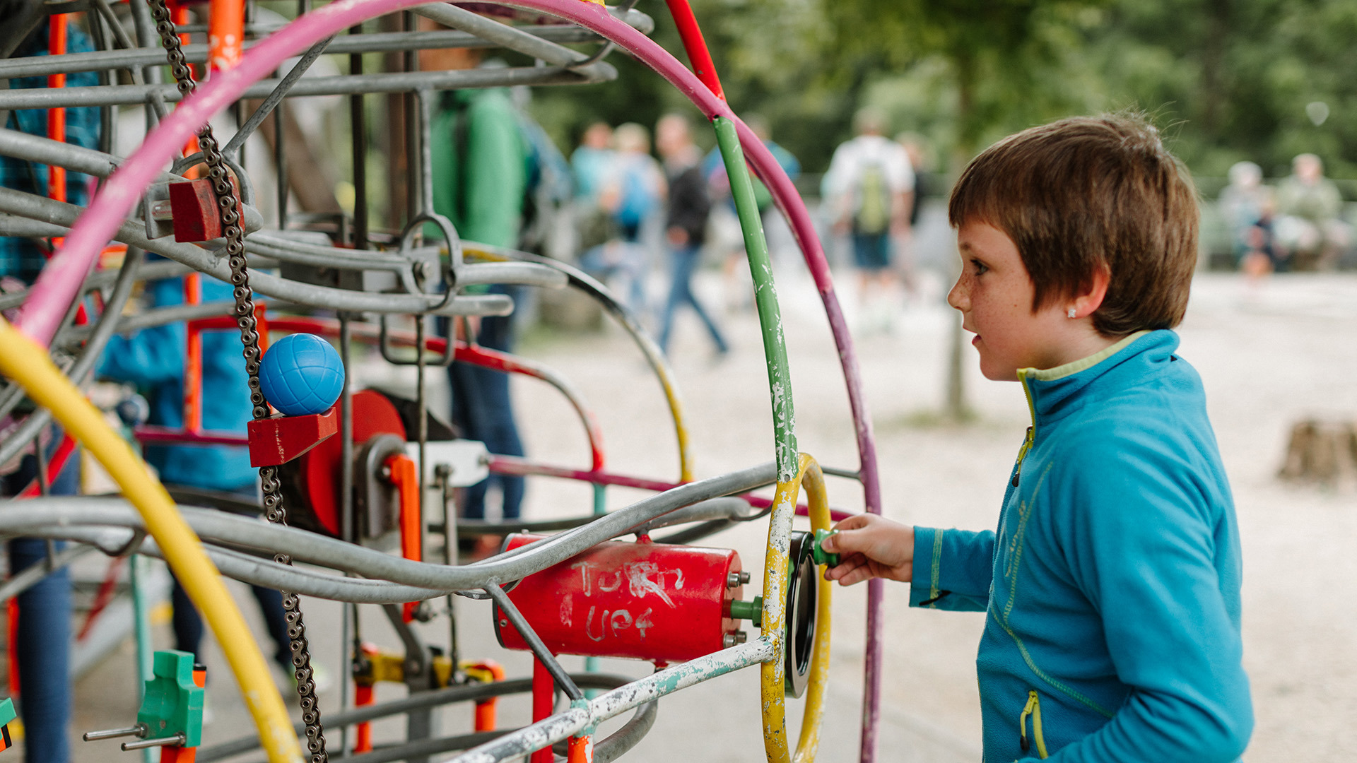 Child turns crank on marble run in playground