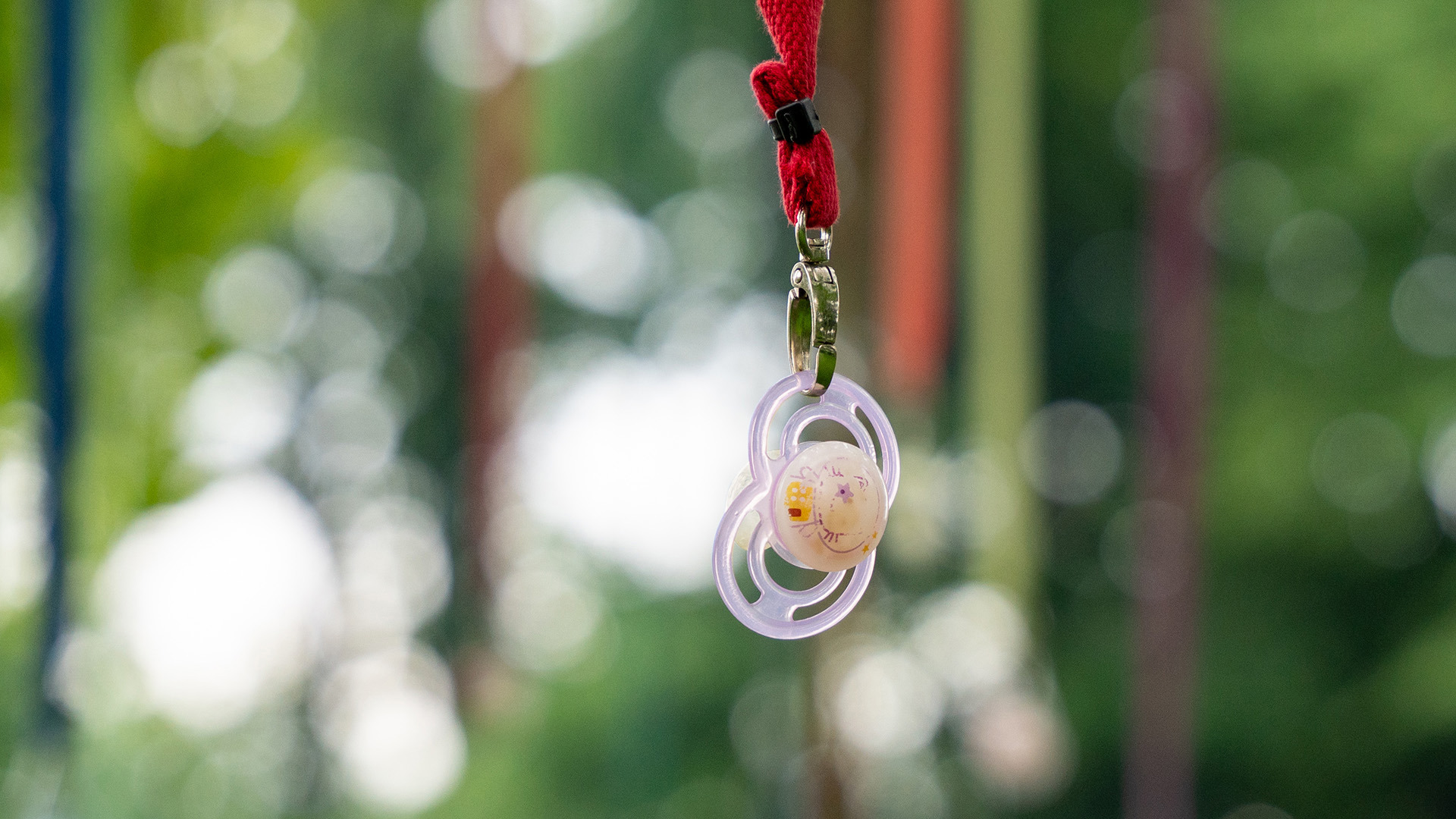 Purple pacifier on the Nuggibaum with red strap
