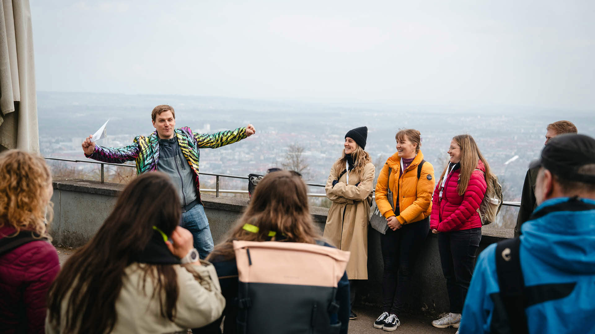 Several people are watching a group leader wearing a colorful chaquet.