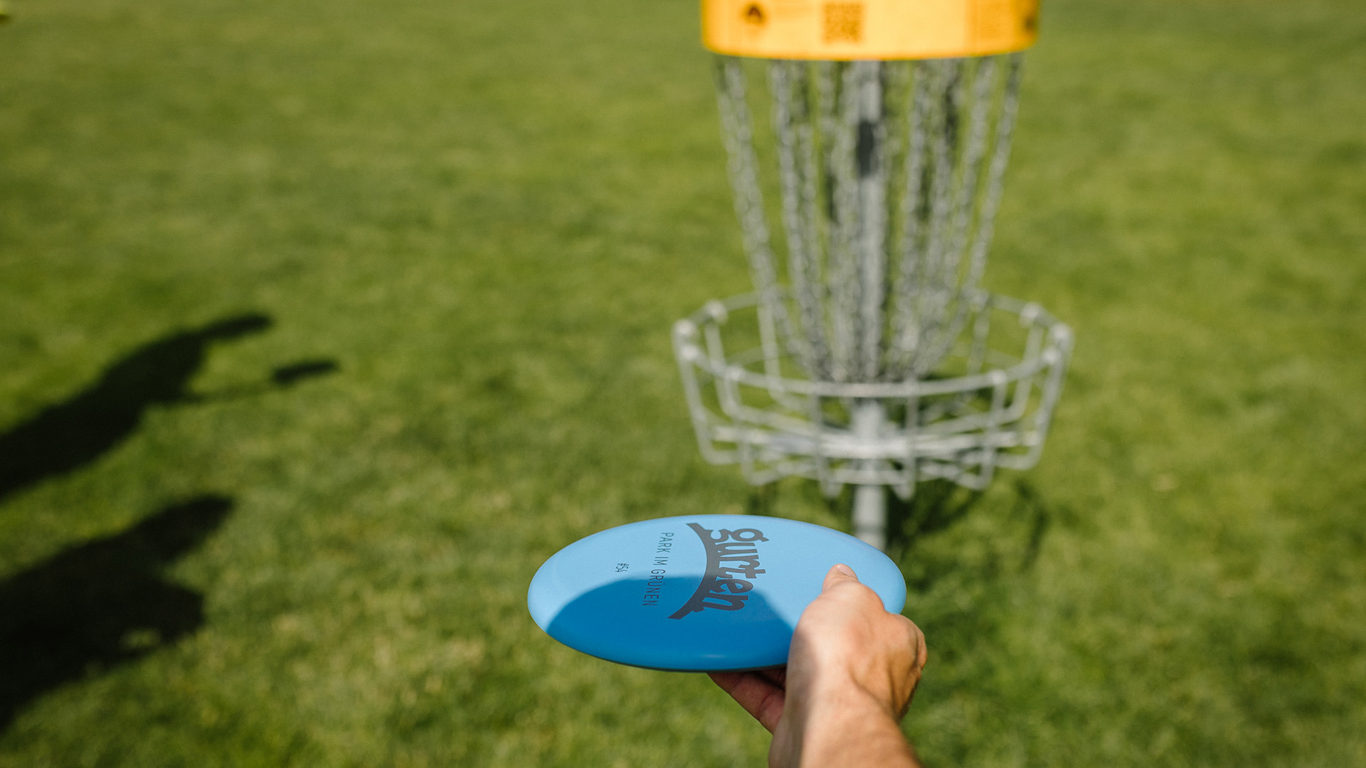 Person trying to throw a blue Frisbee into disc golf baskets